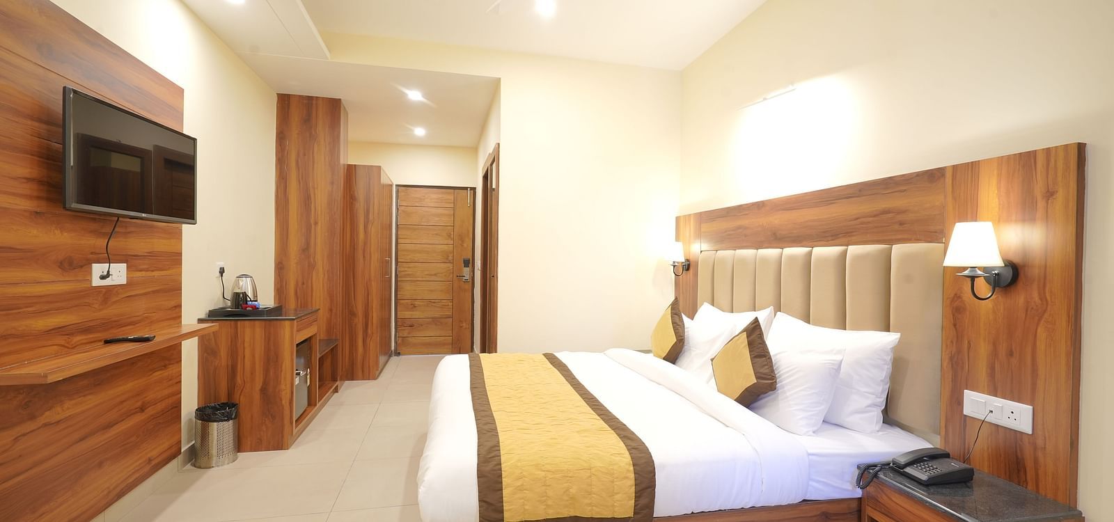 A large bed in front of the TV near a nightstand Deluxe Room at DLS Oak Bush, Musssoorie.