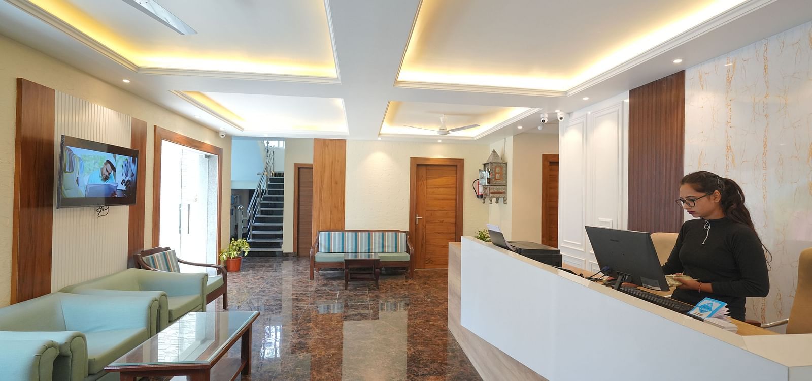 Reception area with a receptionist standing near the desk at DLS Oak Bush, Mussoorie.