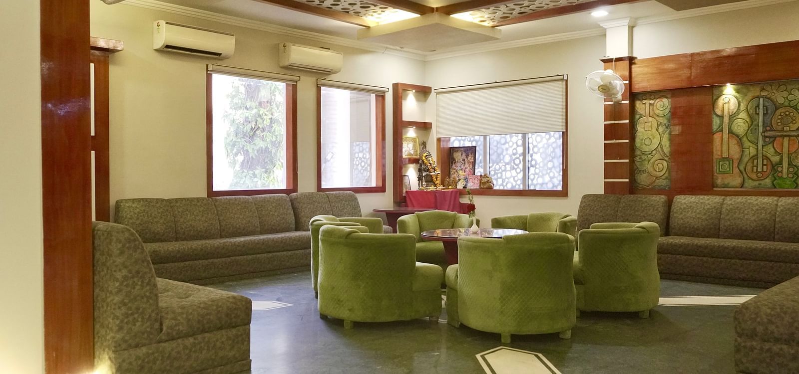 A hotel lobby with plush green sofas and armchairs arranged around a coffee table  | DLS Park Grace, Haridwar 
