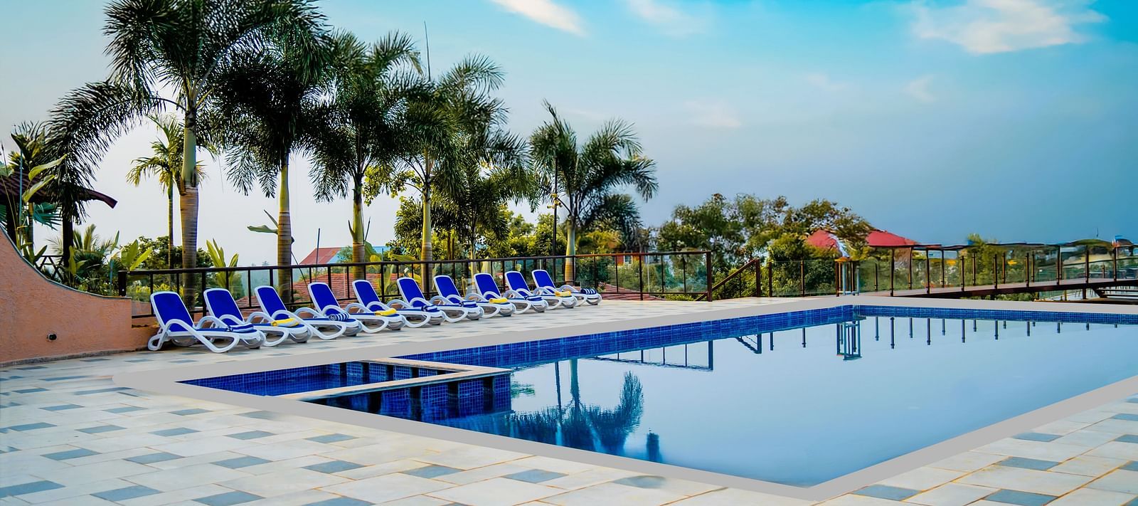 A beautiful pool on a sunny day, with coconut tree and beach beds in the image - Crescent Resort, Goa