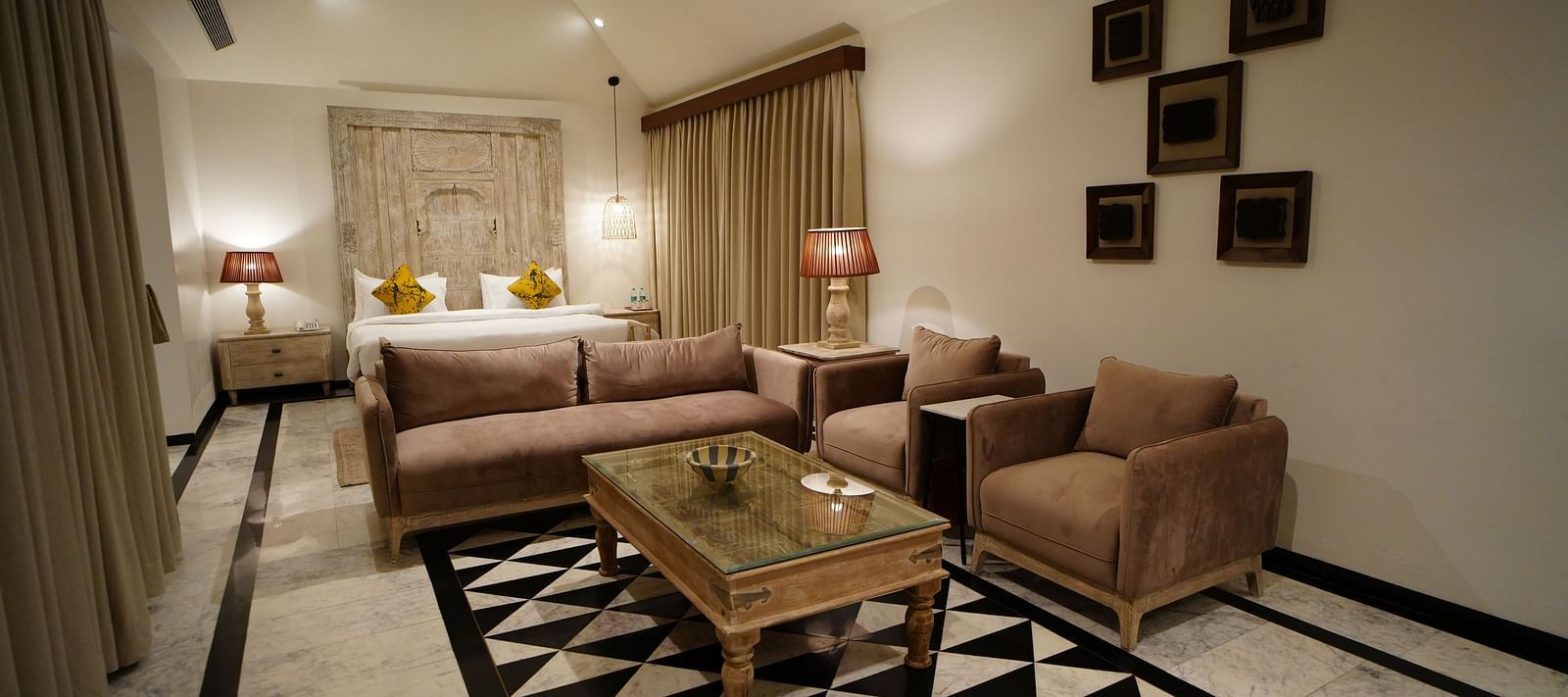 A room with a bed and a seating area with sofa in front at Surpura Bagh.
