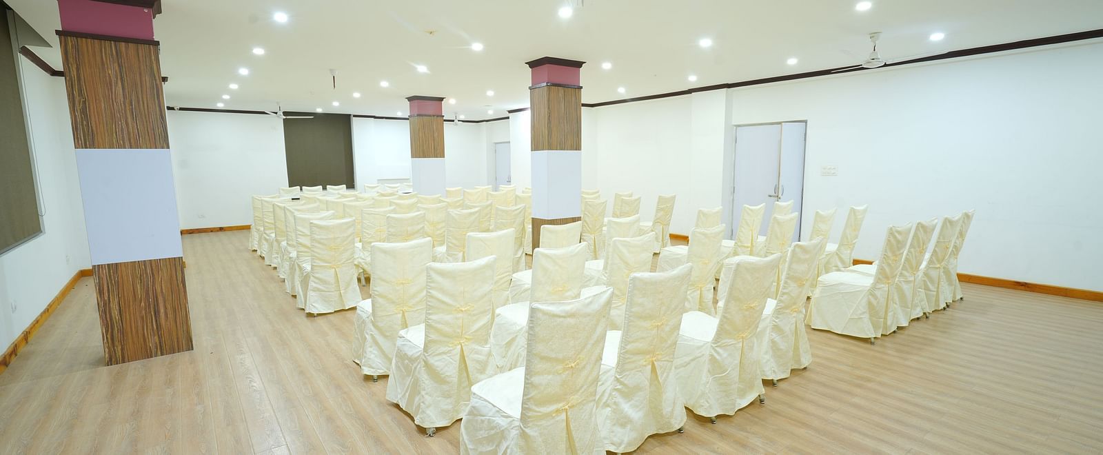 A large, empty banquet hall with rows of chairs set up on a wooden floor | DLS Hotel Shiva Sanctuary & Spa, Dharamshala