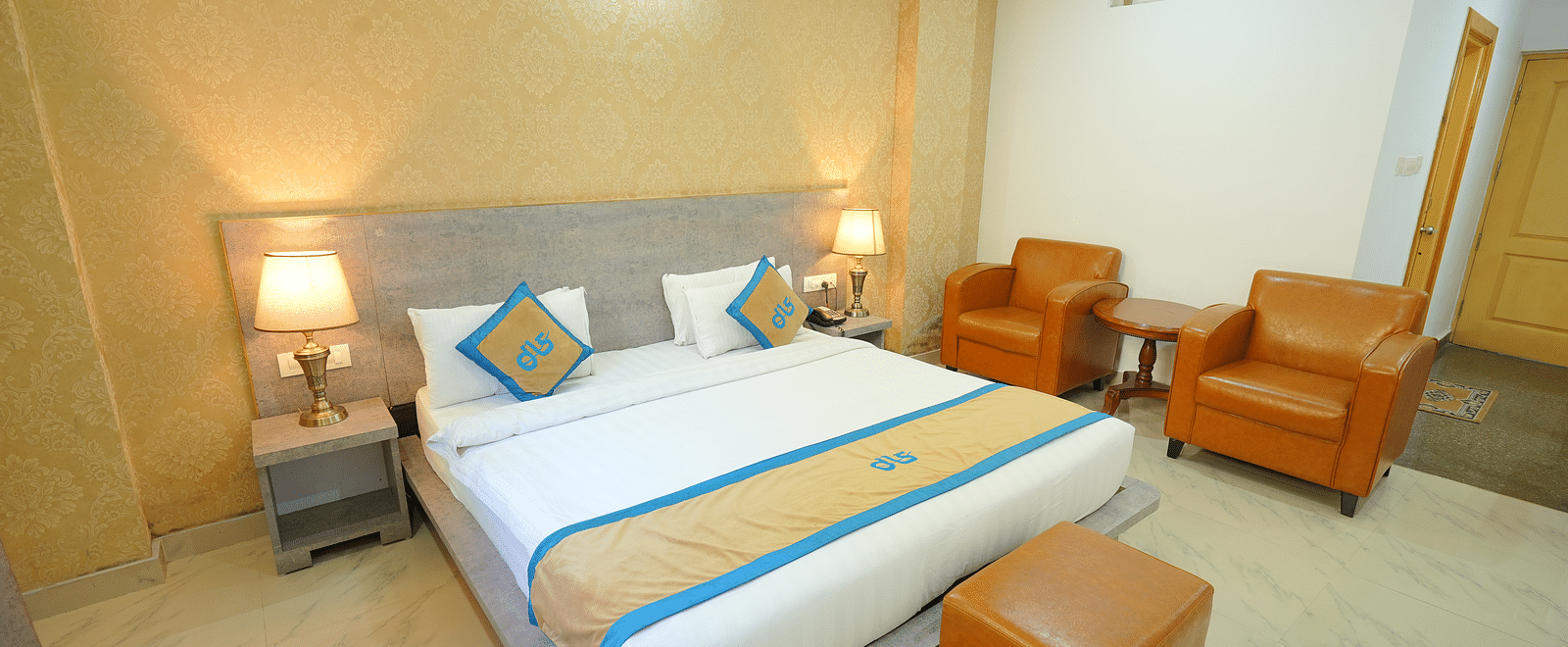 A side angle shot o the king size bed in the room along with two couches | DLS Hotel Shiva Sanctuary & Spa, Dharamshala
