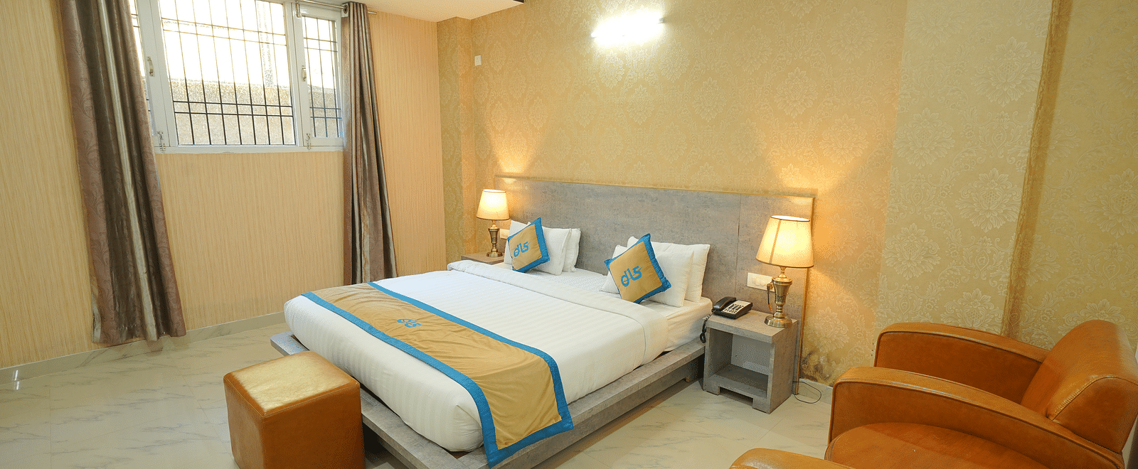 Image of the deluxe room featuring a king size bed, marble flooring and two couches | DLS Hotel Shiva Sanctuary & Spa, Dharamshala