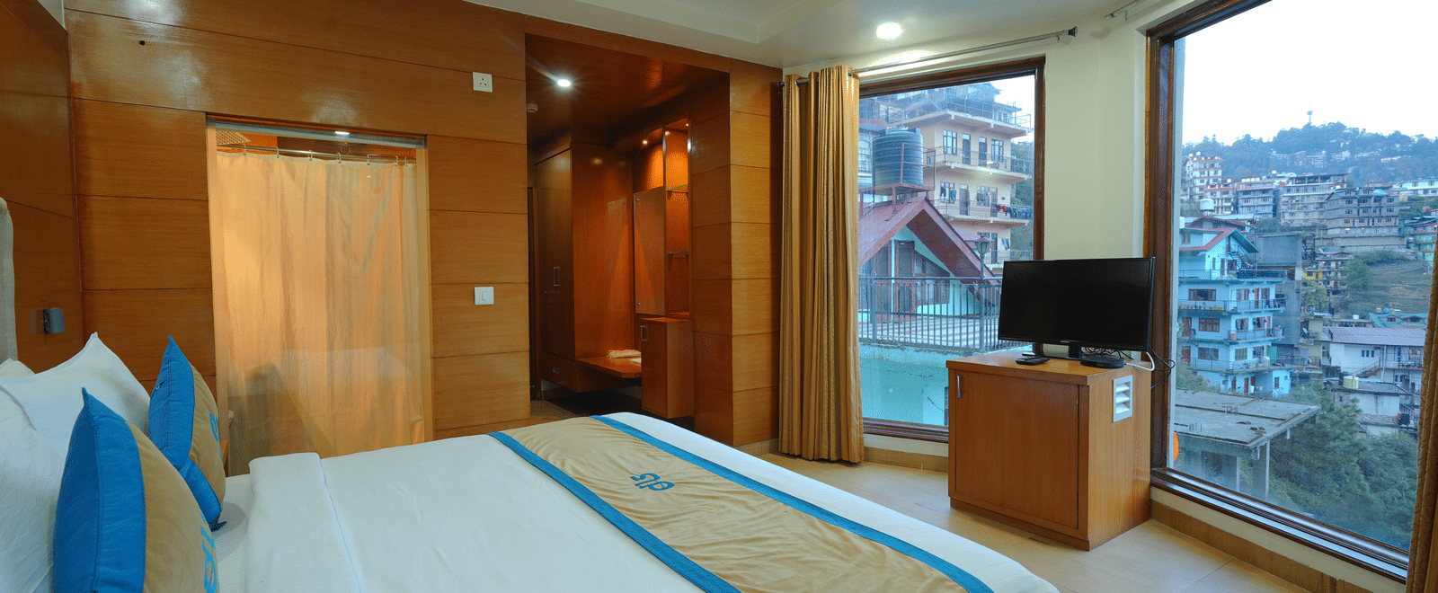 A bedroom showcasing the view through glass windows and a TV on a table at DLS Hotels The Rock Castle.