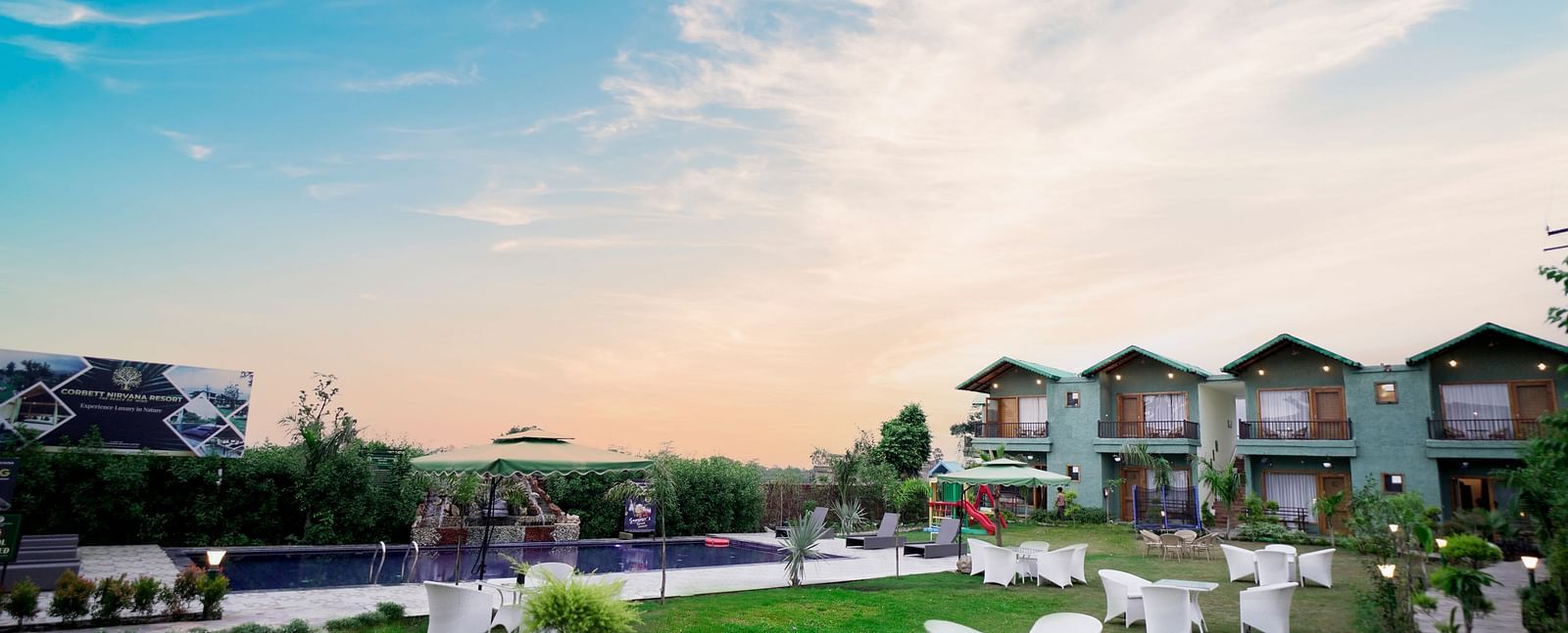 A resort with multiple buildings, well-maintained green lawns, and outdoor seating under a clear blue sky.