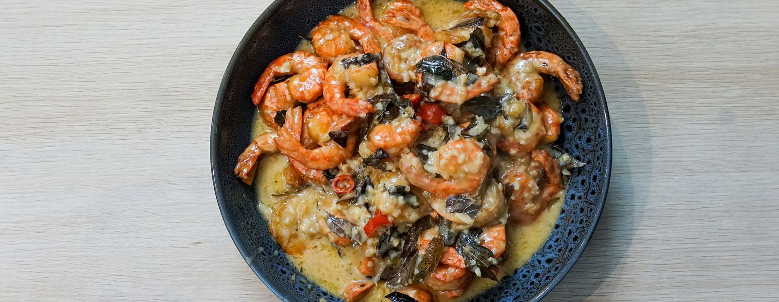 An aerial view of a prawn curry in a bowl kept on a table.