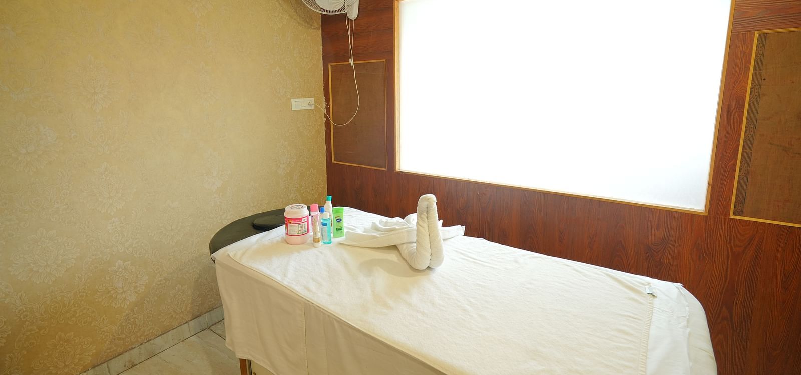 A spa room with a massage table made up with fresh linens and a decorative towel swan | DLS Hotel Shiva Sanctuary & Spa, Dharamshala