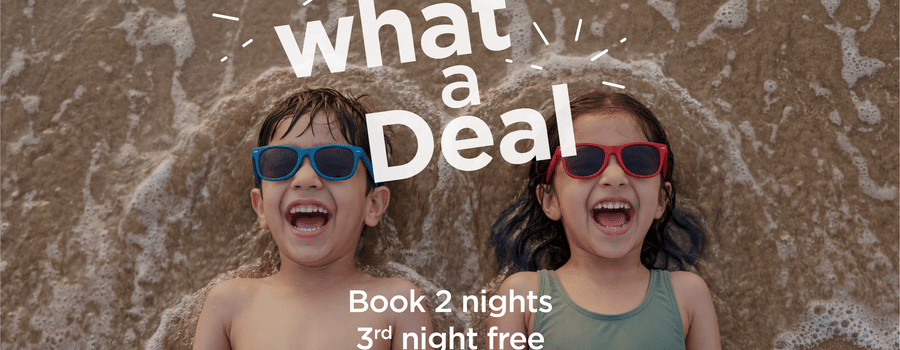 Sarovar Hotels What a Deal offer banner with two kids on the beach, stay 2 nights get the 3rd night free plus 15% off on F&B and kids up to 10 stay free.