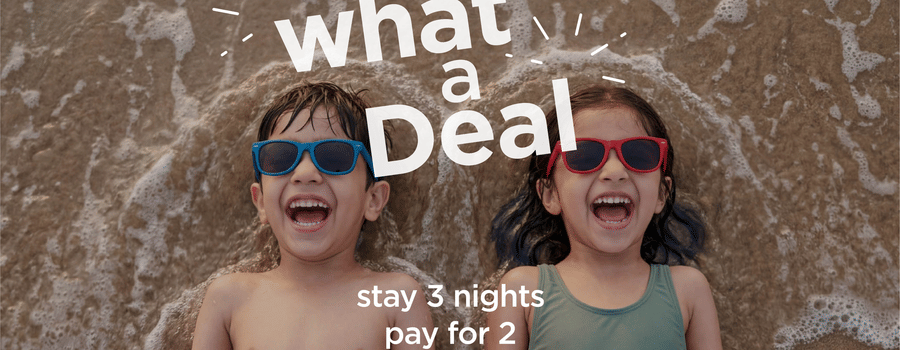 Sarovar Hotels What a Deal offer banner with two kids on the beach, stay 2 nights get the 3rd night free plus 15% off on F&B and kids up to 10 stay free.