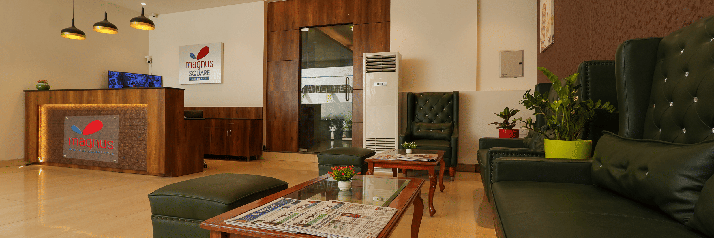 A lobby at Magnus Square, Viman Nagar featuring sofa set with centre table and a reception desk at one corner.
