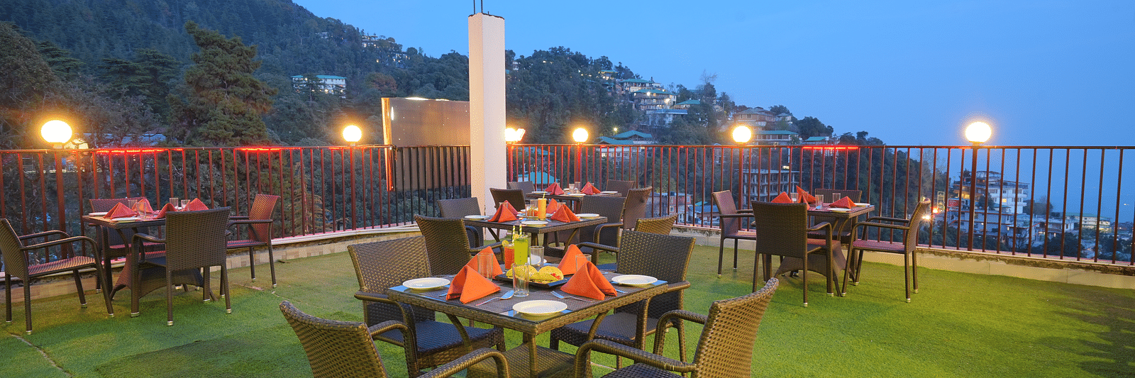 Image of a rooftop restaurant with a scenic view at dusk | DLS Hotel Shiva Sanctuary & Spa, Dharamshala