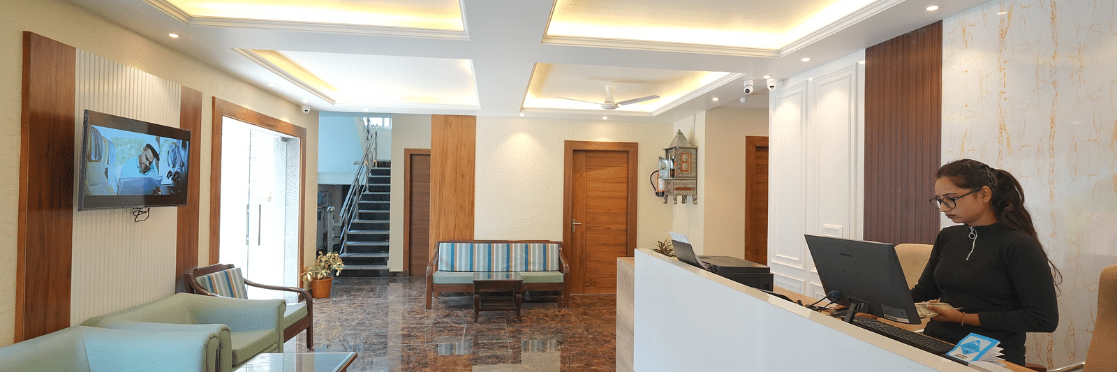Reception area with a receptionist standing near the desk at DLS Oak Bush, Mussoorie.
