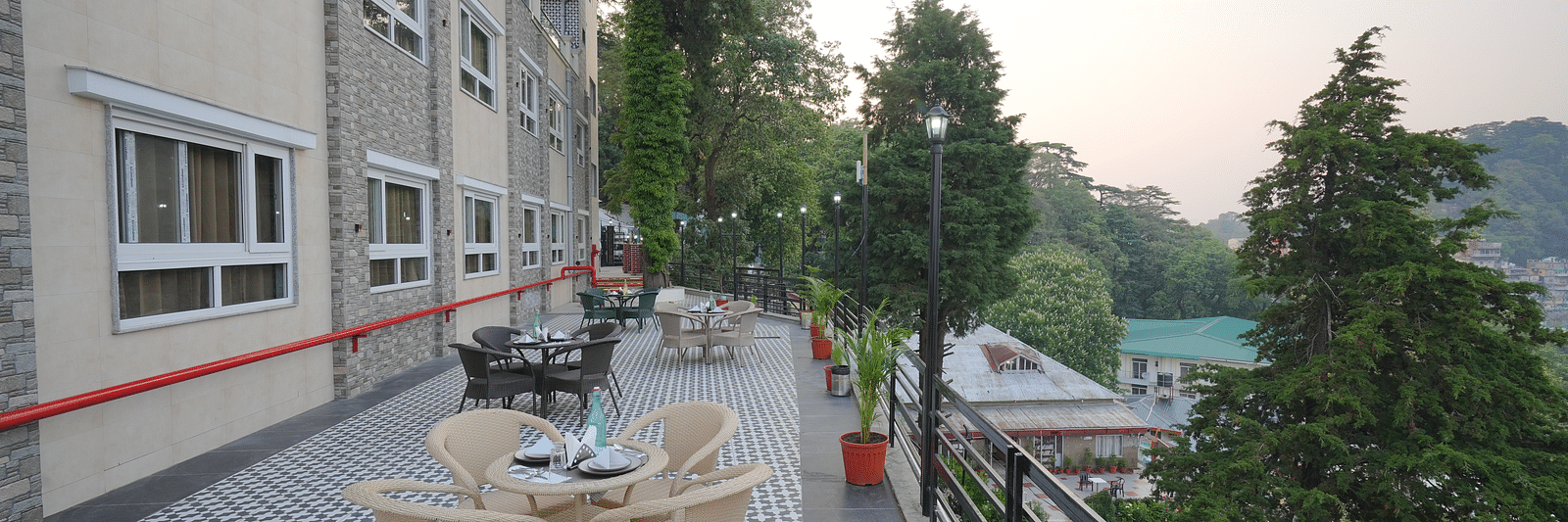 An outside seating area with comfortable chairs around tables at DLS Oak Bush, Mussoorie.