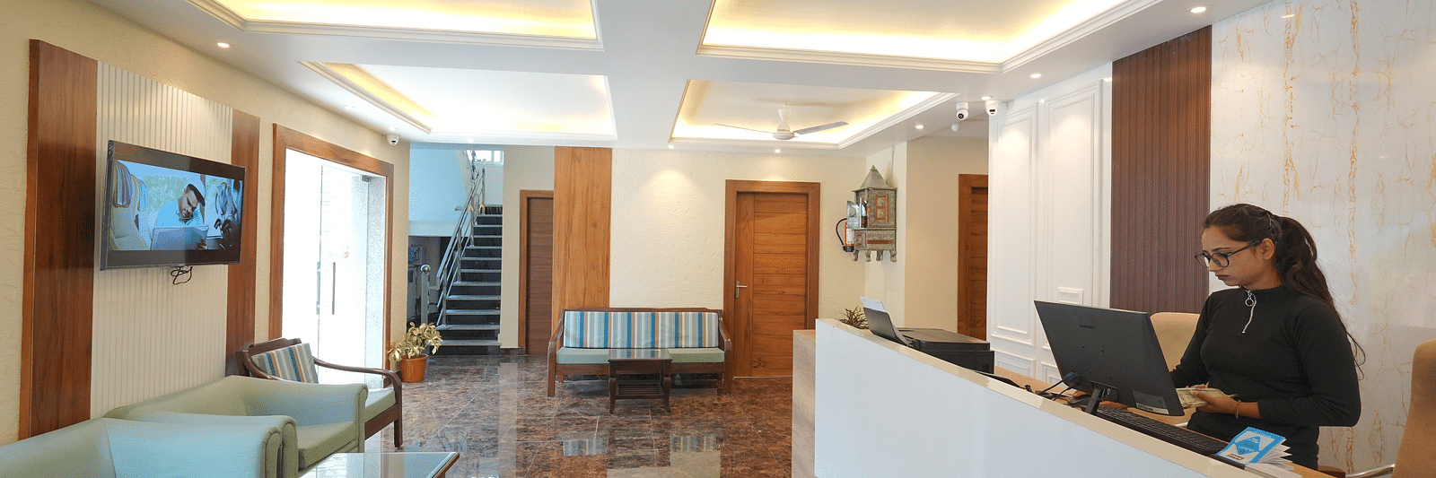 Reception area with a receptionist standing near the desk at DLS Oak Bush, Mussoorie.