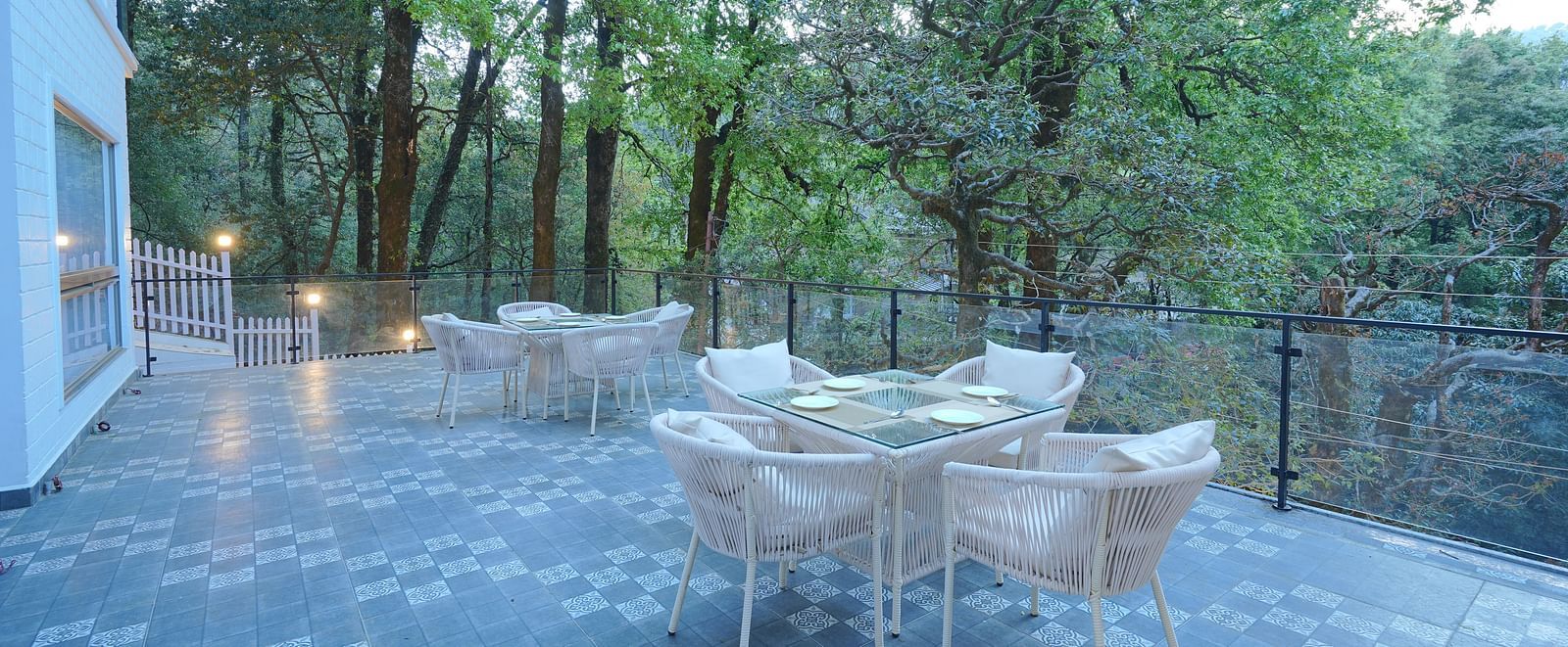 The deck at DLS The Emerald, Nainital featuring chairs and tables surrounded by trees