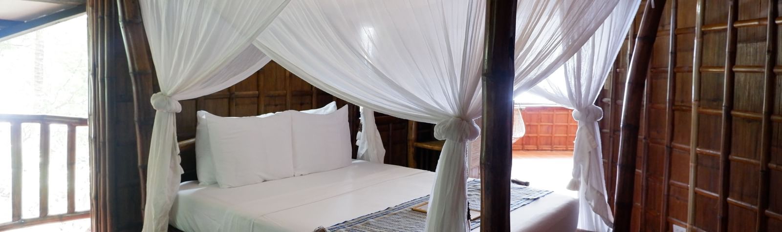 Charming wooden room with canopy bed and balcony view at Flower Island Resort.