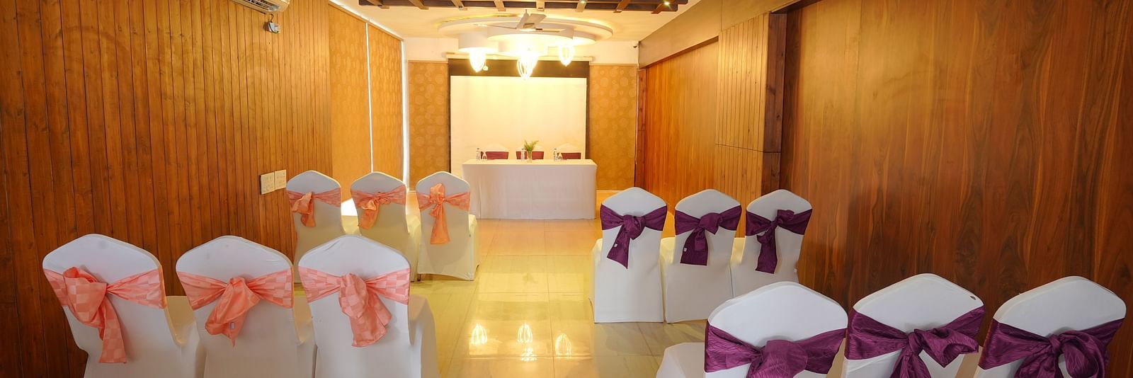 An image of the Whispering Wind Hall at DLS Whispering Winds with chairs, air-conditioning, and bright yellow lighting