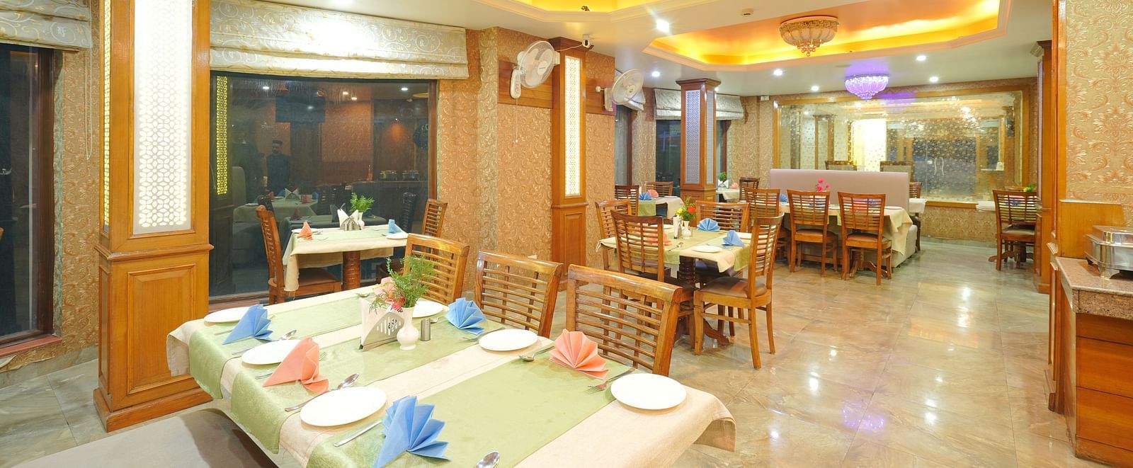 Dining area with a table set with cutlery, chairs, and soft yellow lighting from the ceiling at DLS Hotels The Rock Castle.