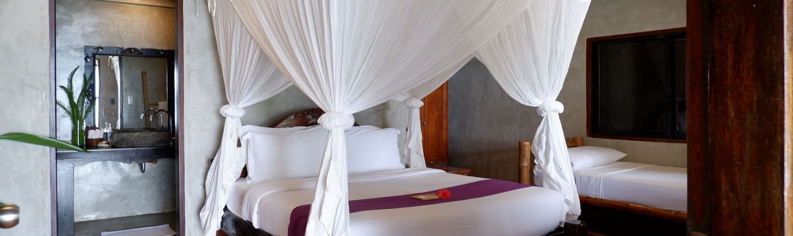 Elegant villa interior with twin canopy beds and polished wooden floors at Flower Island Resort.