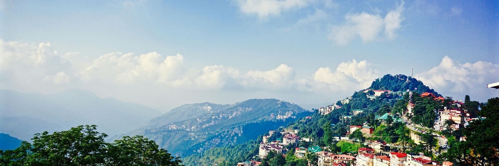 a beautiful landscape of shimla with vast blue skies and mountain ranges