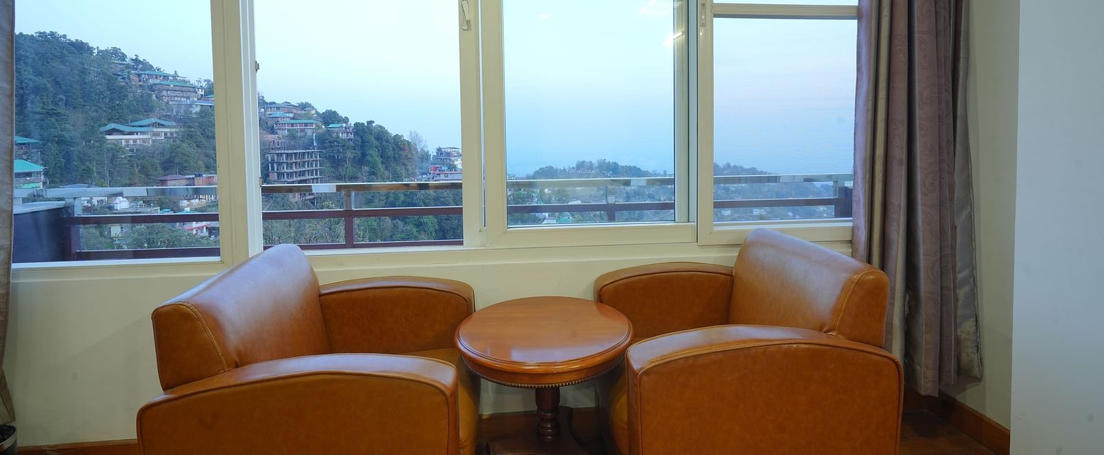 A cosy seating area with two armchairs and a small table in front of a large window | DLS Hotel Shiva Sanctuary & Spa, Dharamshala