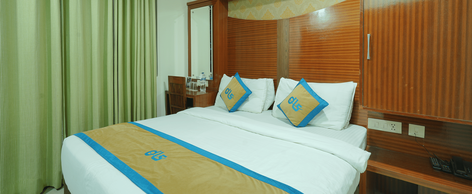 Deluxe room featuring a wooden headboard, a dressing table, a chair, and a mirror next to the bed at DLS Hotels The Rock Castle.