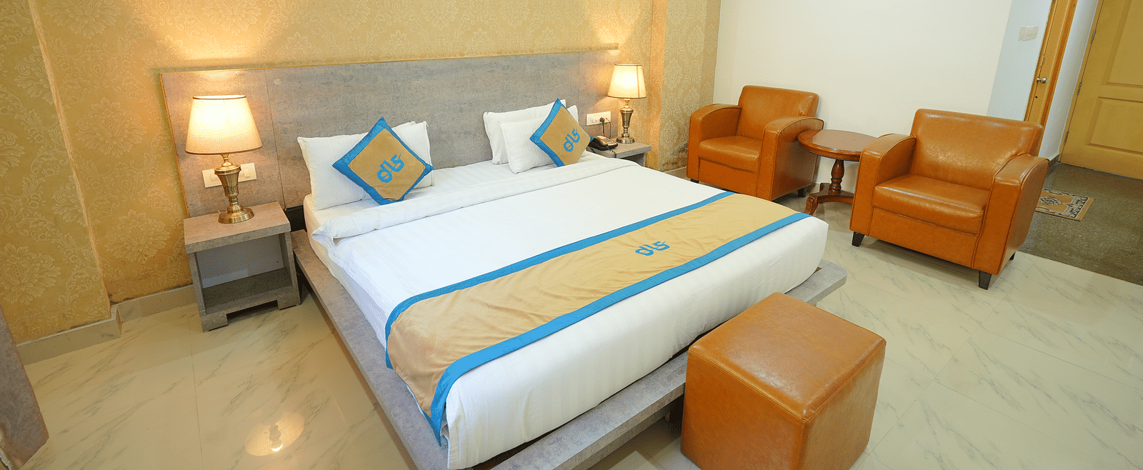 A side angle shot o the king size bed in the room along with two couches | DLS Hotel Shiva Sanctuary & Spa, Dharamshala