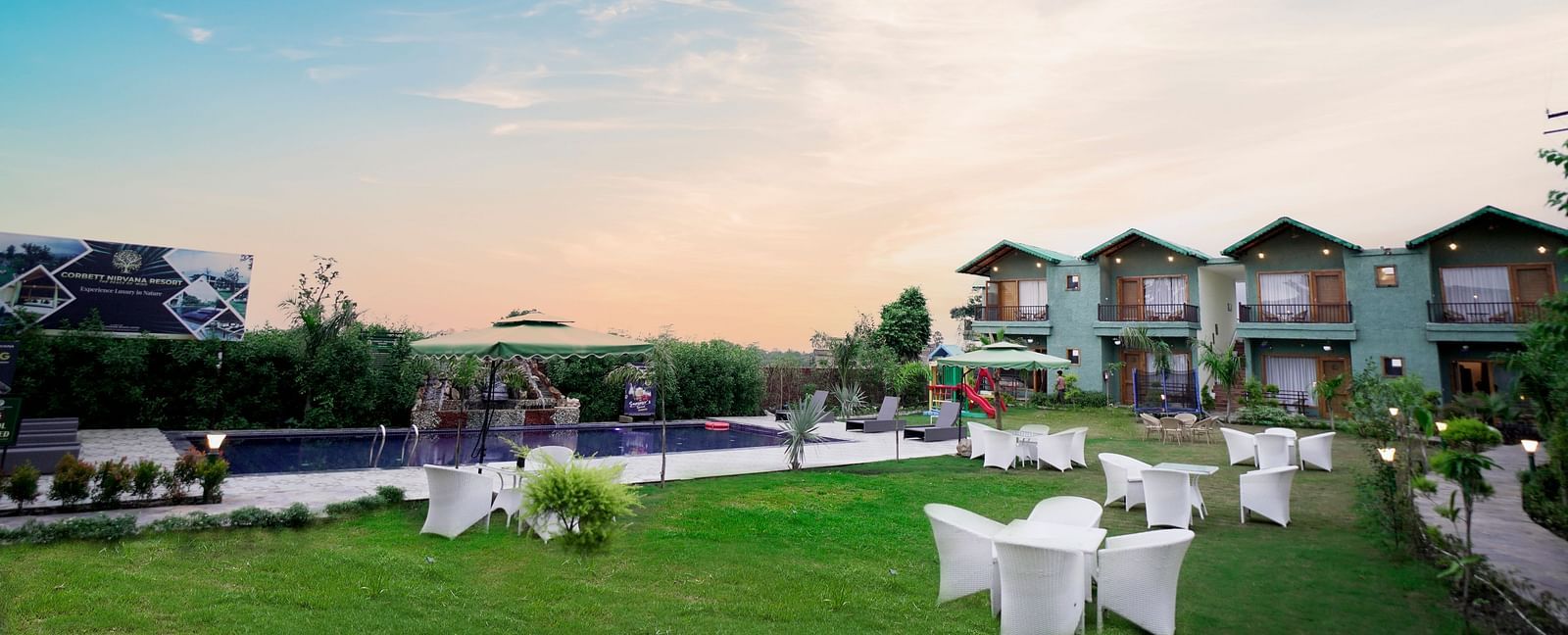 A resort with multiple buildings, well-maintained green lawns, and outdoor seating under a clear blue sky.