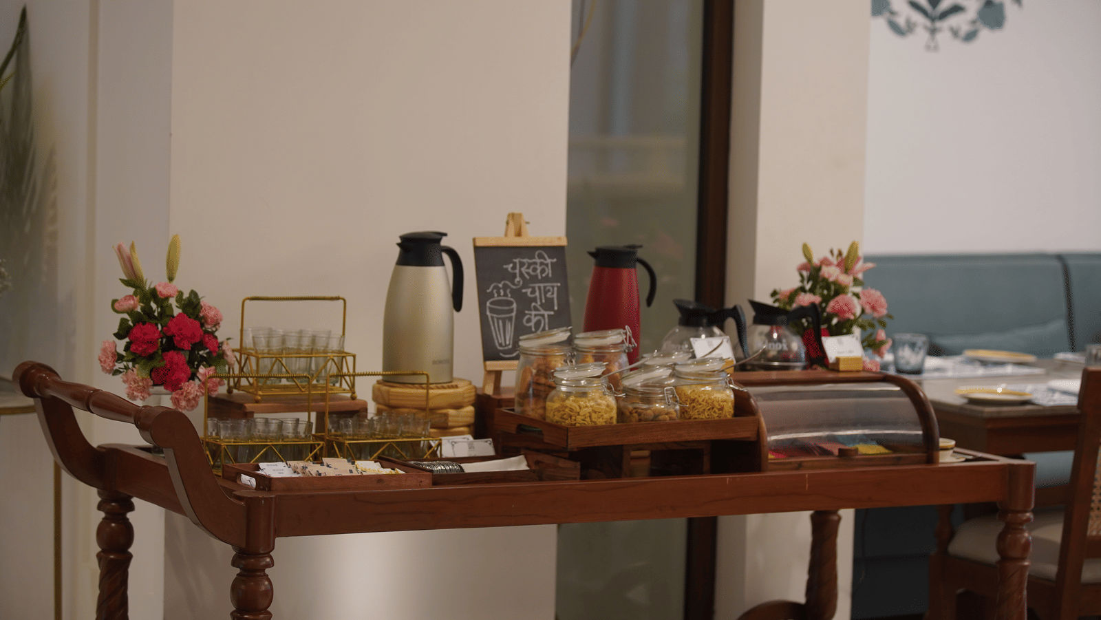 A wooden cart at Bhagirathi by Atishay featuring jars of food and jugs next to tea glasses and bouquets