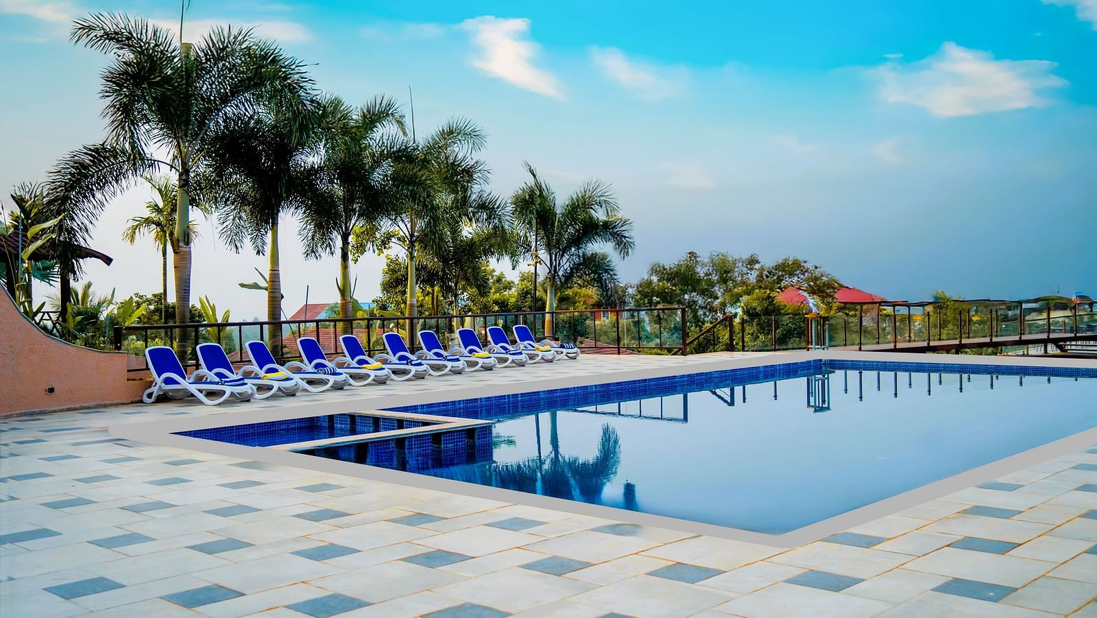 A beautiful pool on a sunny day, with coconut tree and beach beds in the image - Crescent Resort, Goa