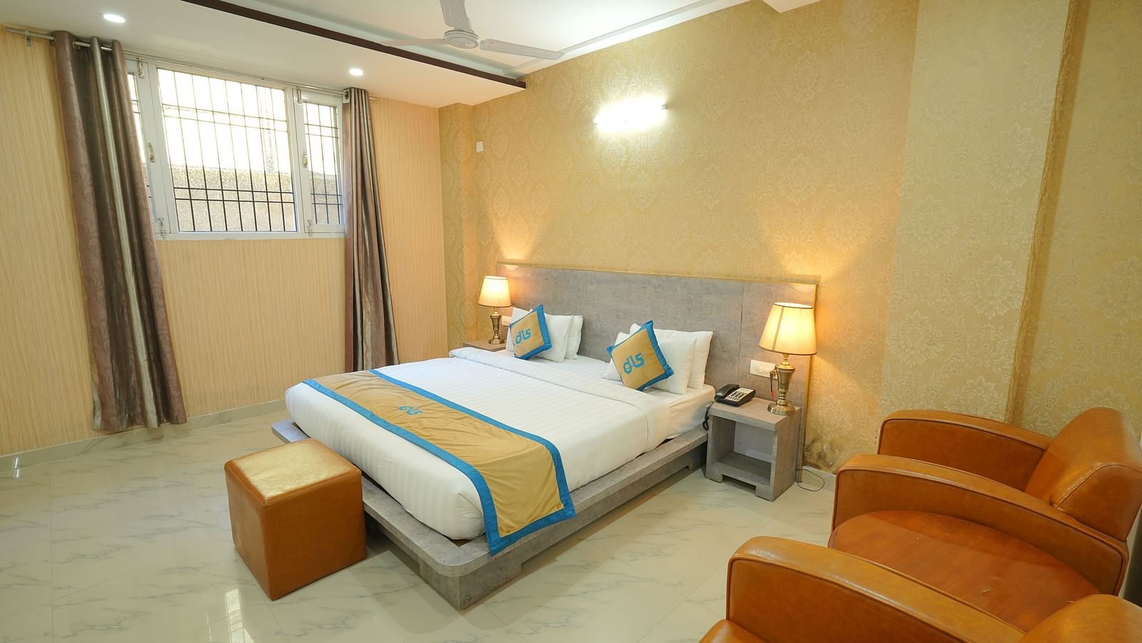 Shot of deluxe room featuring king size bed, bed side lamps, two couches and a window | DLS Hotel Shiva Sanctuary and Spa