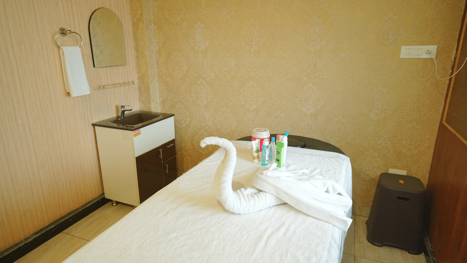 A spa room with a massage table made up with fresh linens and a decorative towel swan | DLS Hotel Shiva Sanctuary & Spa, Dharamshala