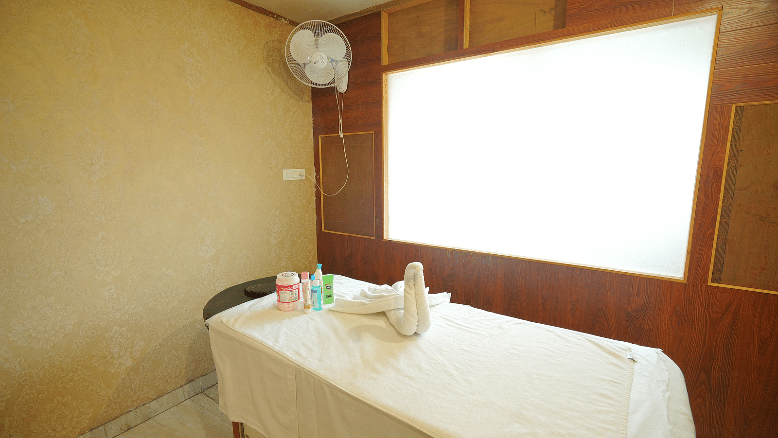 A spa room with a massage table made up with fresh linens and a decorative towel swan | DLS Hotel Shiva Sanctuary & Spa, Dharamshala