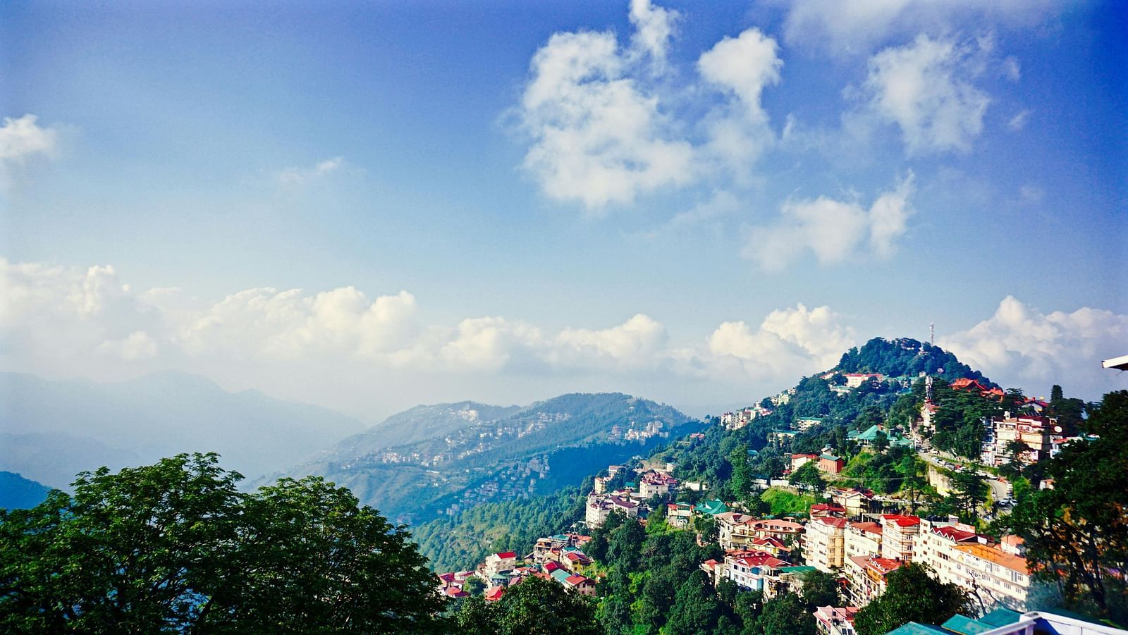 a beautiful landscape of shimla with vast blue skies and mountain ranges