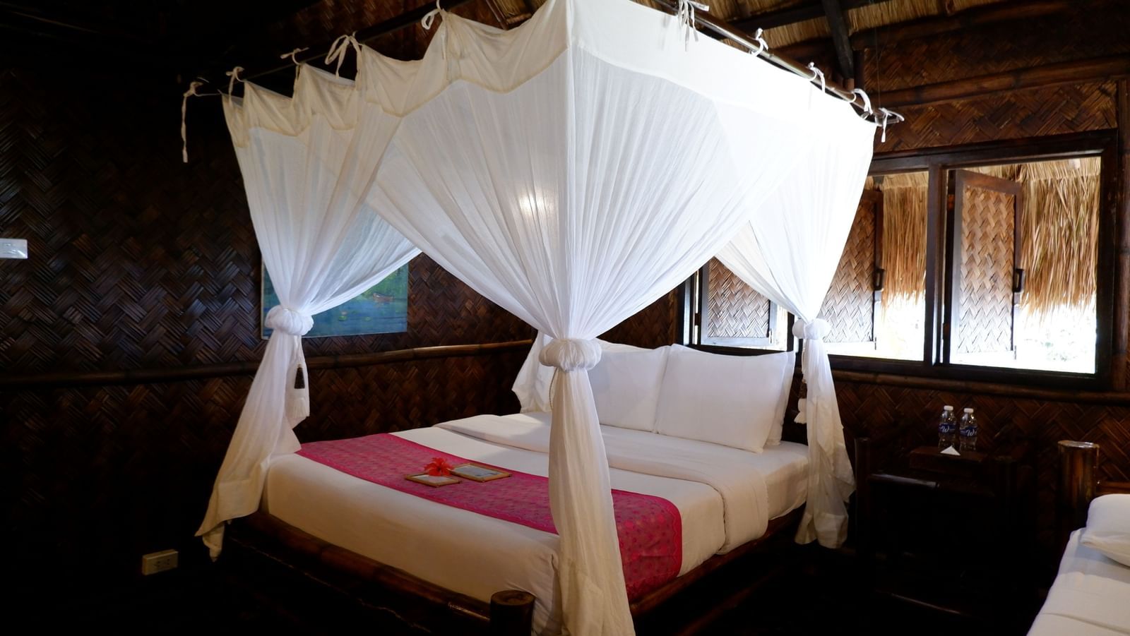 Elegant four-poster bed in a rustic tropical suite at Flower Island Resort. 