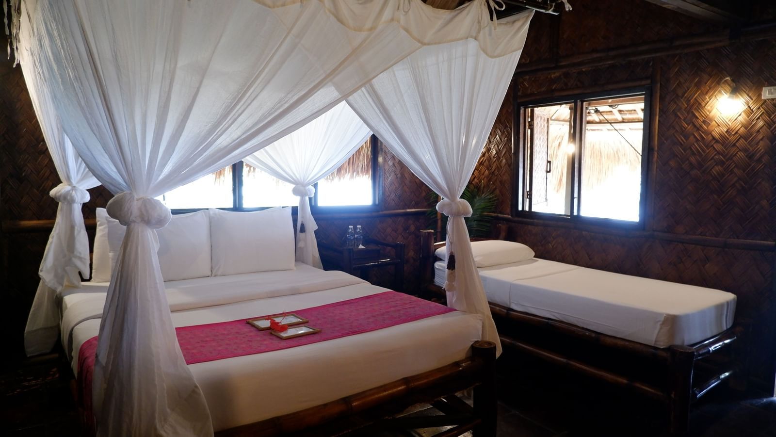 Tropical bedroom with mosquito netting and large windows at Flower Island Resort.