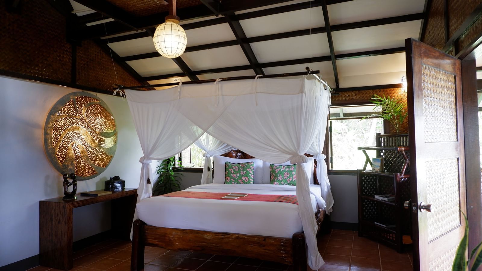 Bright bamboo suite with large bed and handcrafted decor at Flower Island Resort.