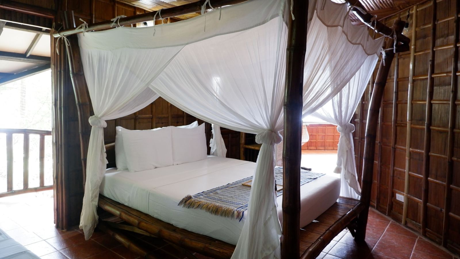 Charming wooden room with canopy bed and balcony view at Flower Island Resort.