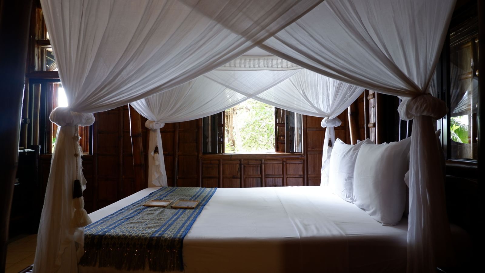 Spacious bedroom with canopy bed and garden views at Flower Island Resort.