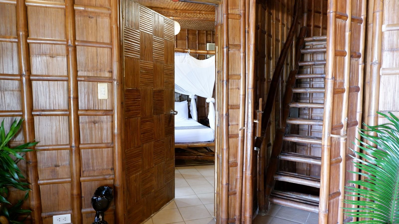 Rustic wooden staircase and hallway inside a bamboo villa at Flower Island Resort.