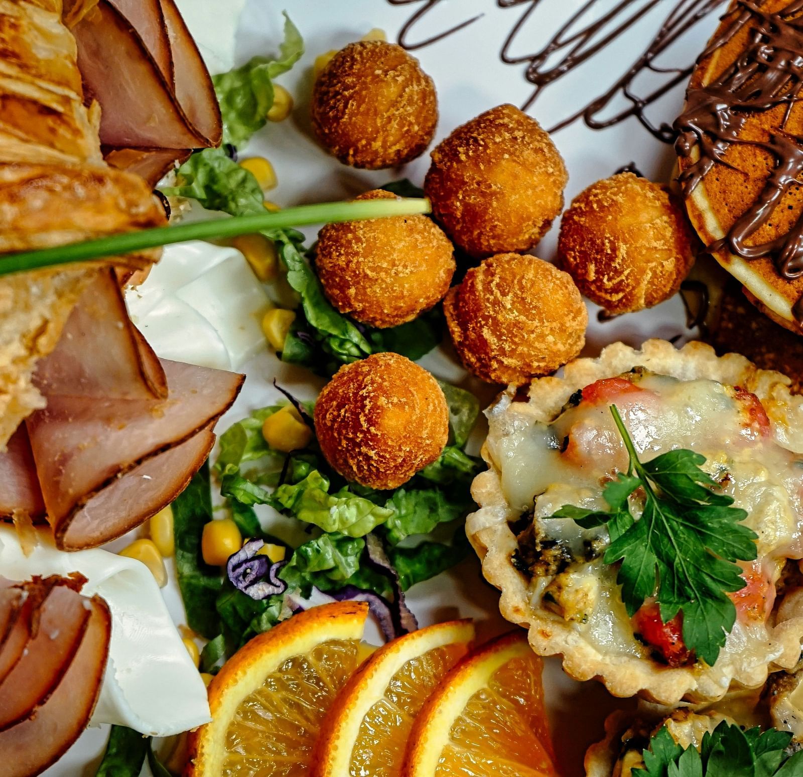 A close-up of a breakfast or brunch spread with croissants, pastries, savory tarts, and sweet dishes