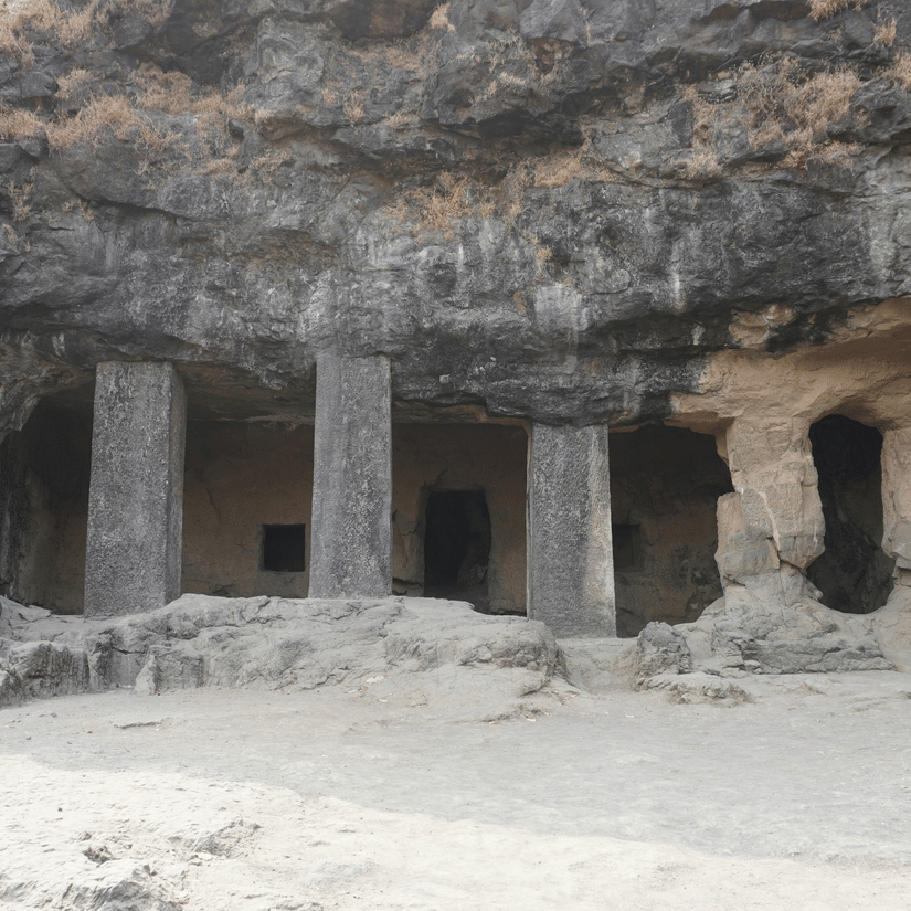 A view from afar of the entrance to a cave with pillars carved out of the mountain in view. The Pandavleni Caves timings are from 8:00 Am to 6:00 PM.