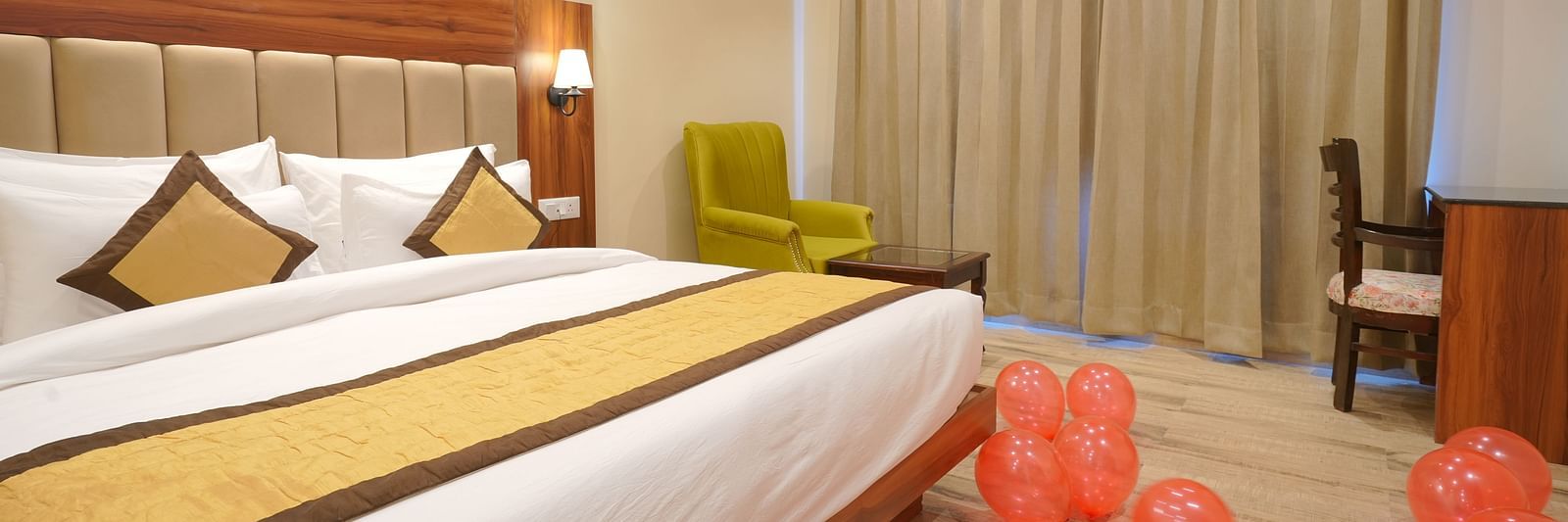 A large bed near a comfortable chair in Deluxe Room at DLS Oak Bush, Musssoorie.