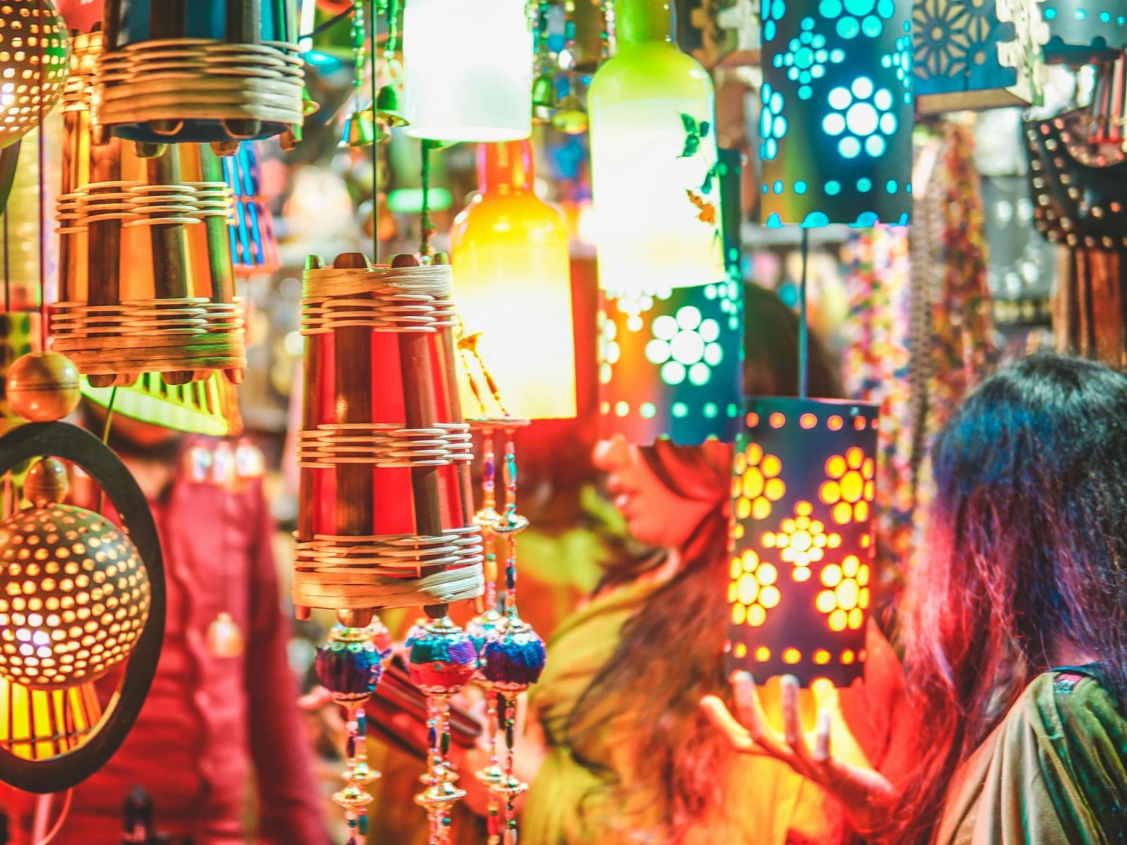 Assorted pendant lanterns in market with customers looking at it.