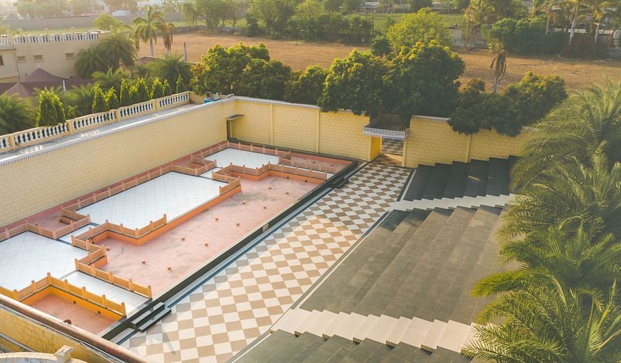 An image of an outdoor amphitheatre surrounded by walls and trees on all four sides - The Garden Ananta Elite, Rajkot