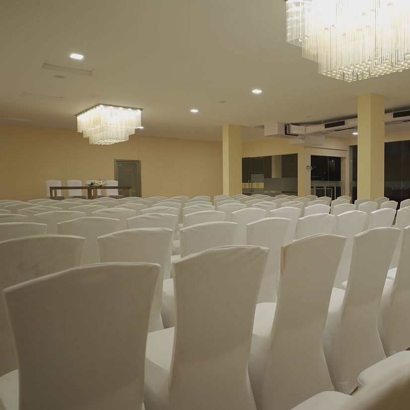 Chairs in clean white covers facing the podium at Citrus Classic Resorts and Spa Mahabalipuram ECR in the spacious Apollo Banquet Hall for a conference