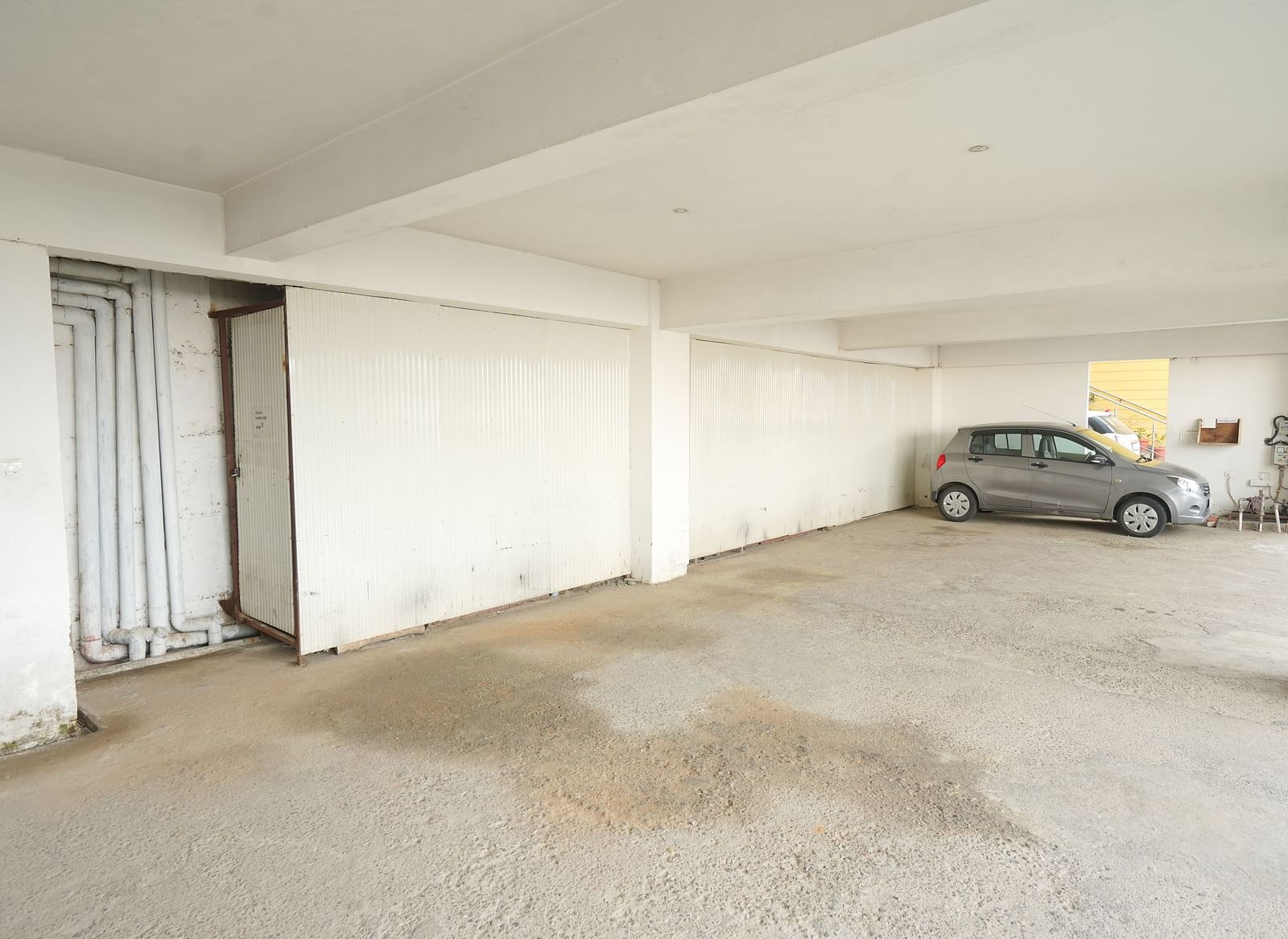 A large, empty parking garage with white walls, and a single car parked in the distance | DLS Hotel Shiva Sanctuary & Spa, Dharamshala