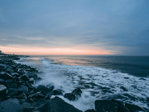 A beach in Pondicherry at dusk with waves crashing the stones on the shore