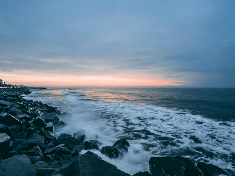 A beach in Pondicherry at dusk with waves crashing the stones on the shore